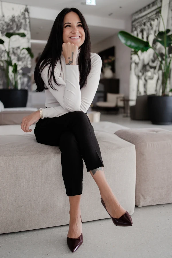 therapist in long top and pants smiles on couch